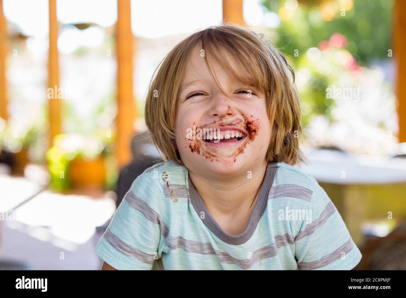 ritratto di sorridente ragazzo di 4 anni con cioccolato sul viso che gioca con la sorella maggiore Foto Stock