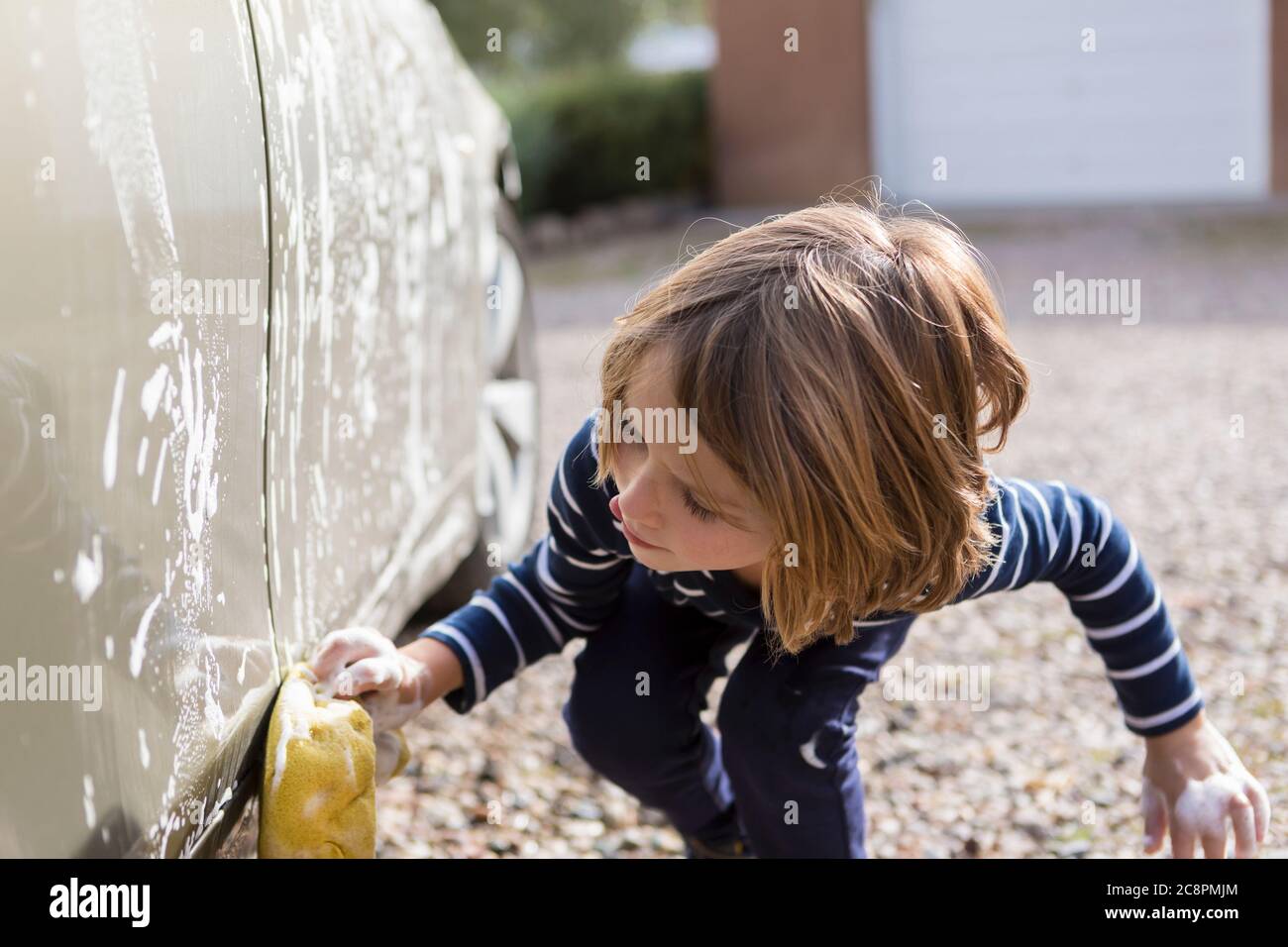 ragazzo di 4 anni che lavava un'auto nel parcheggio Foto Stock