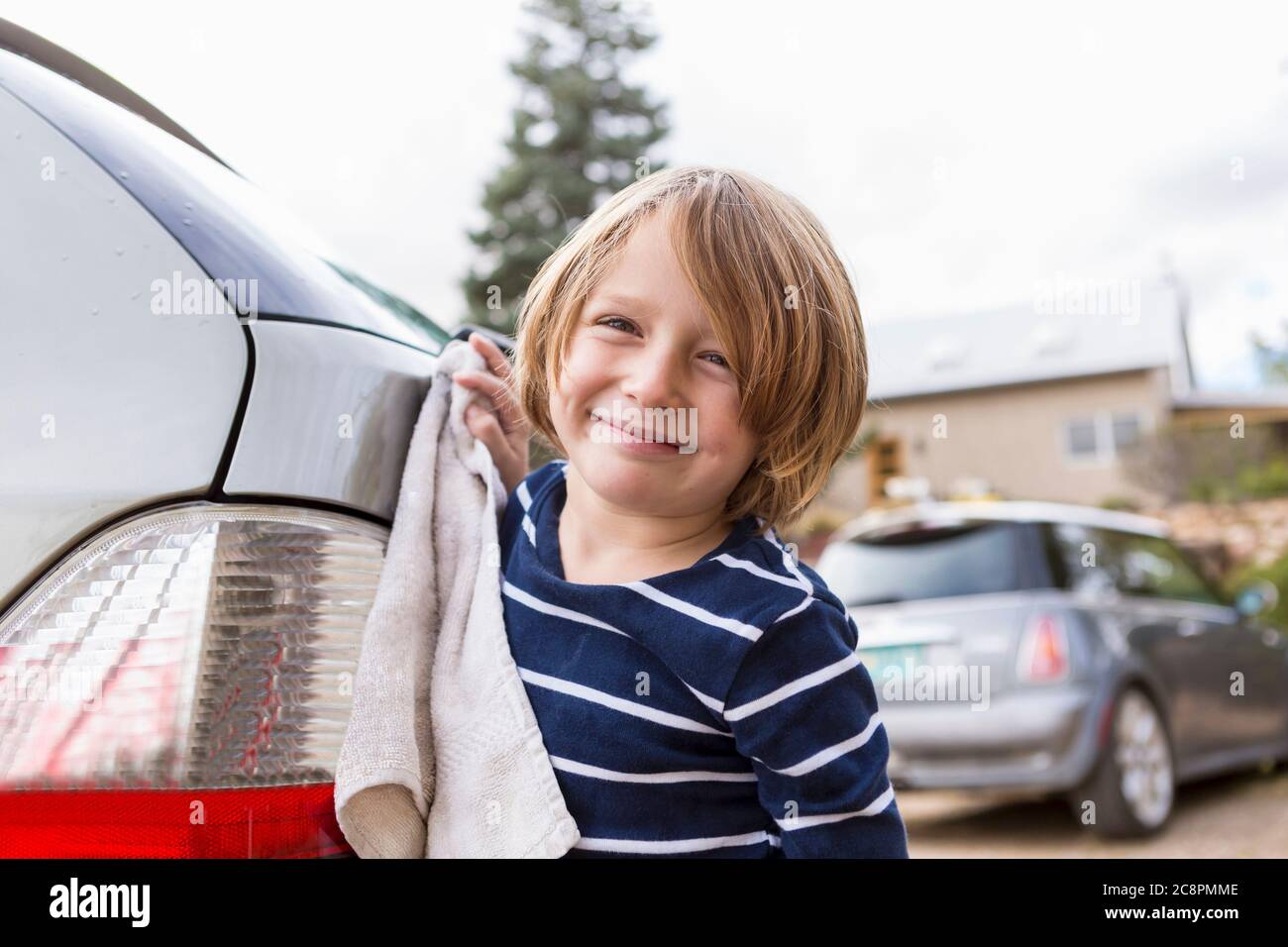 ragazzo di 4 anni che lavava un'auto nel parcheggio Foto Stock