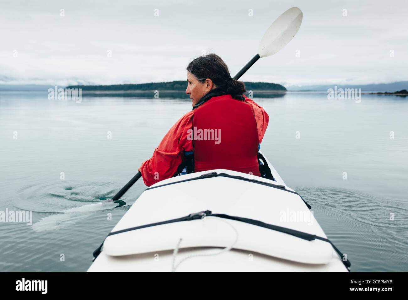 Una donna di mezza età pagaia kayak di mare nelle acque incontaminate di Muir Inlet, Glacier Bay National Park and Preserve, Alaska Foto Stock