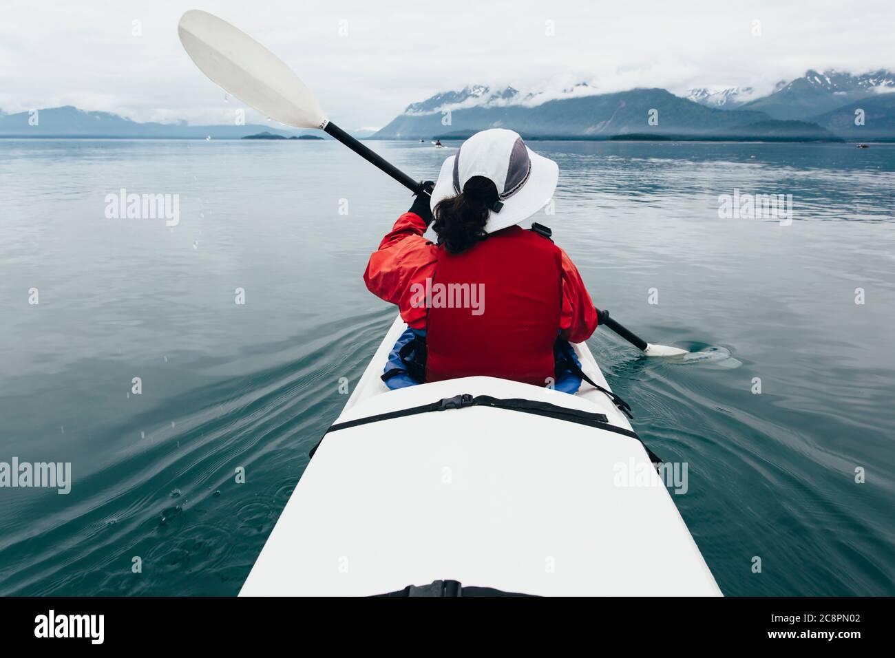 Una donna di mezza età pagaia kayak di mare nelle acque incontaminate di Muir Inlet, Glacier Bay National Park and Preserve, Alaska Foto Stock