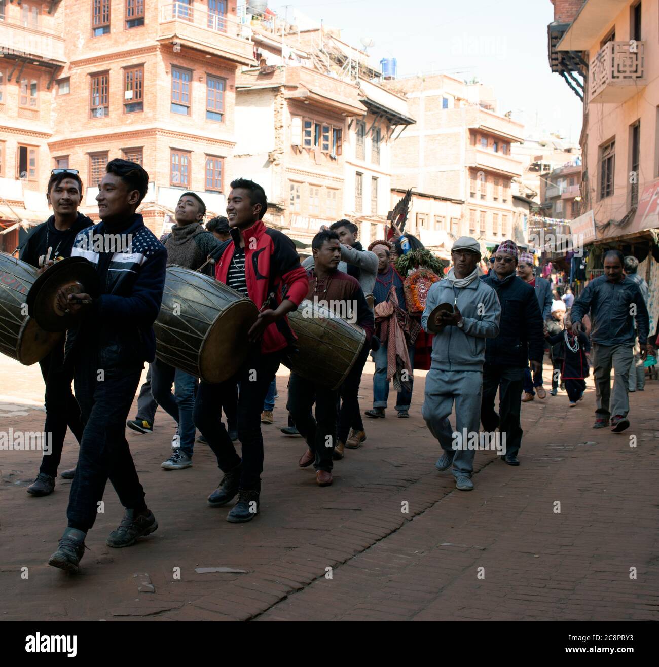 Una processione di strada di musicisti in una calda e soleggiata giornata invernale presso il sito patrimonio dell'umanità dell'UNESCO di Bhaktapur, Nepal. Foto Stock
