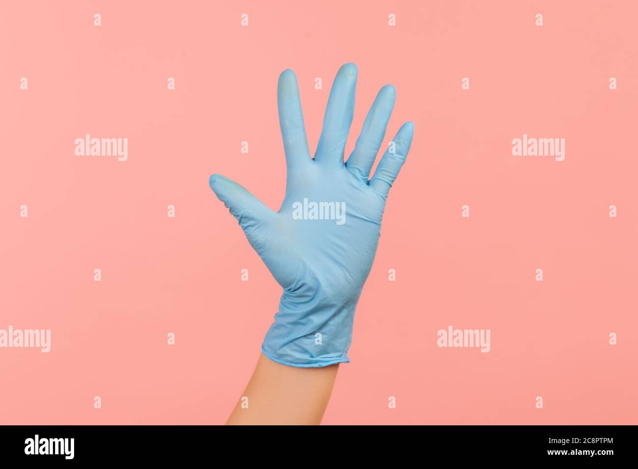 Profilo Vista laterale primo piano della mano umana in guanti chirurgici blu che mostrano il numero cinque con la mano o con la mano che ondeggiano per salutare. Interno, studio shot, isolare Foto Stock