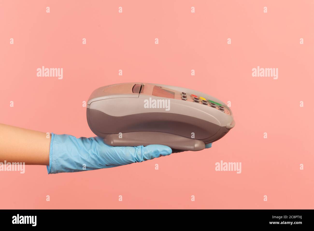 Profilo Vista laterale primo piano della mano umana in guanti chirurgici blu che tengono in posizione POS o terminale di pagamento o pay pass dispositivo. Interno, studio shot, isolato su p Foto Stock