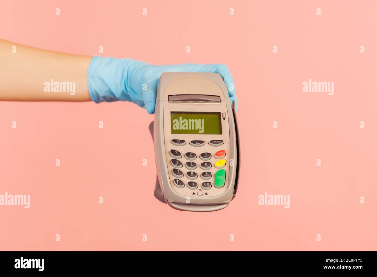Profilo Vista laterale primo piano della mano umana in guanti chirurgici blu che tengono in posizione POS o terminale di pagamento o pay pass dispositivo. Interno, studio shot, isolato su p Foto Stock