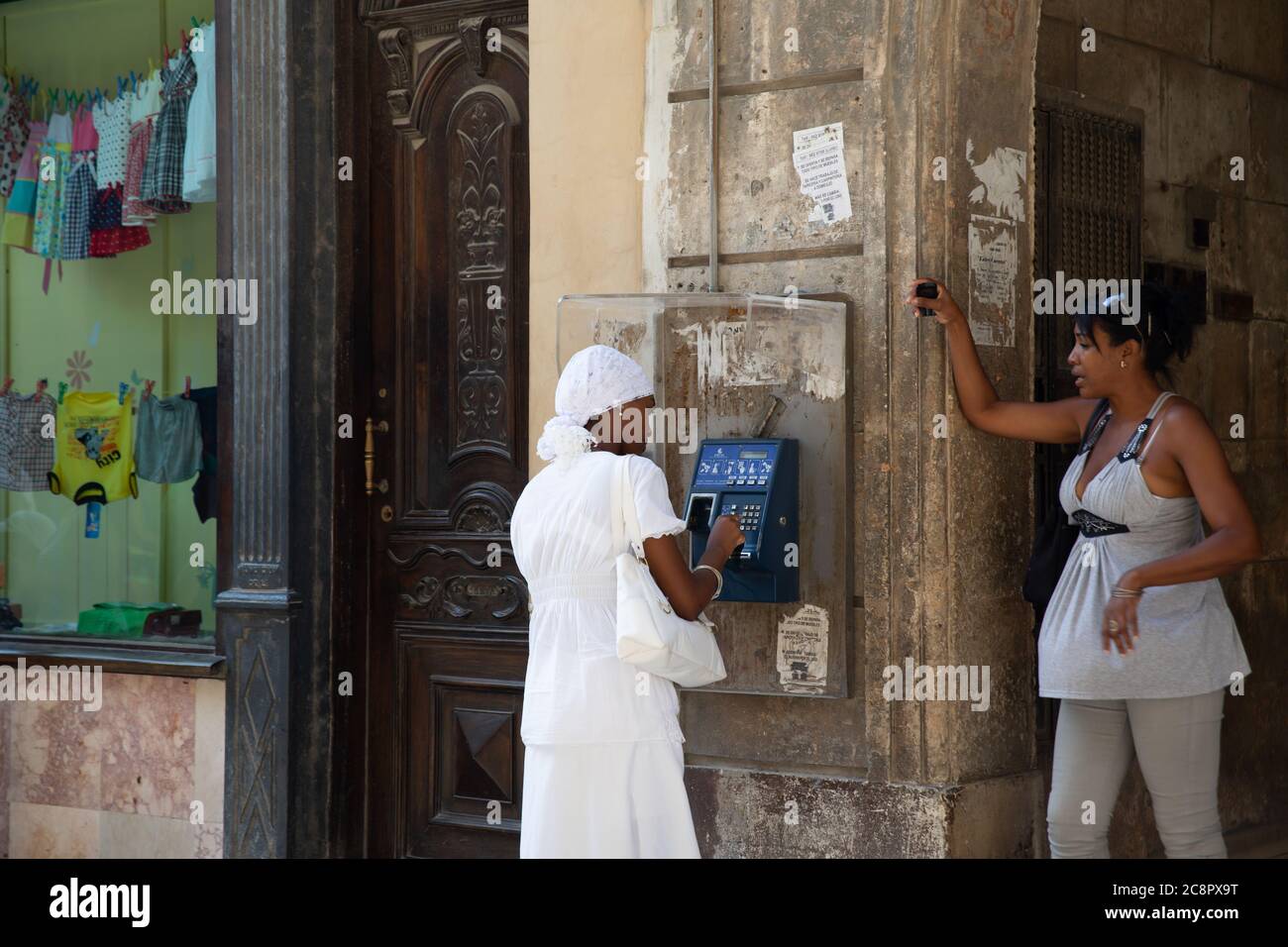 L'Avana / Cuba - 04.15.2015: Giovane cubana che indossa un abito bianco Santeria facendo una telefonata su un telefono pubblico Foto Stock