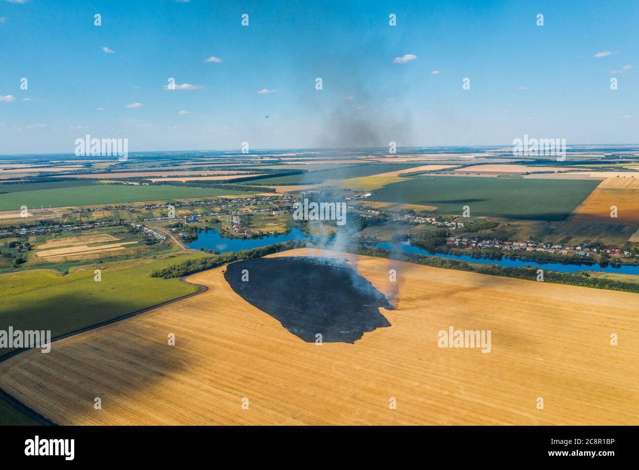 Campo agricolo in fuoco, vista aerea. Campo di segale agricolo che brucia con fumo. Foto Stock