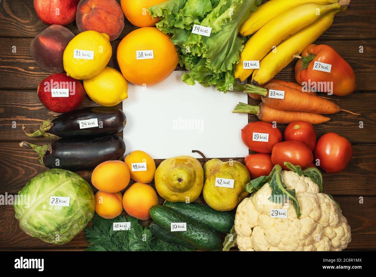 Diversi tipi di frutta e verdura crude con etichette calorie su tavola di legno e carta bianca vuota come spazio di copia per il tuo testo. Dieta, cibo sano biologico vegetariano concetto. Foto Stock