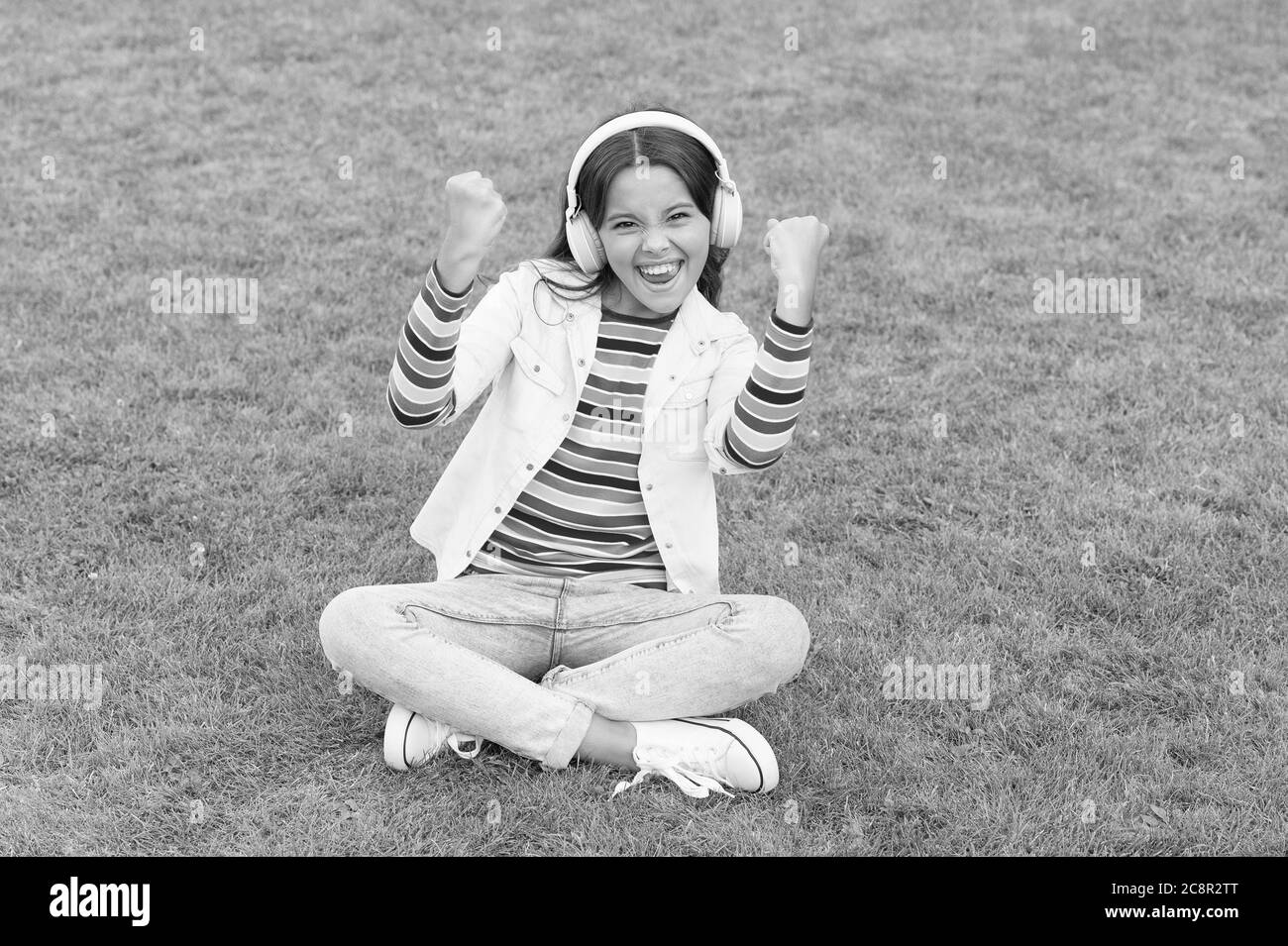 Stile di vita sano e relax. Ragazza yoga. Piccolo bambino in cuffia. Playlist estiva. Godetevi la natura primaverile all'aperto. Libro audio per lo studio dei bambini. Nuova tecnologia. Bambino ascoltare musica su erba verde. Foto Stock