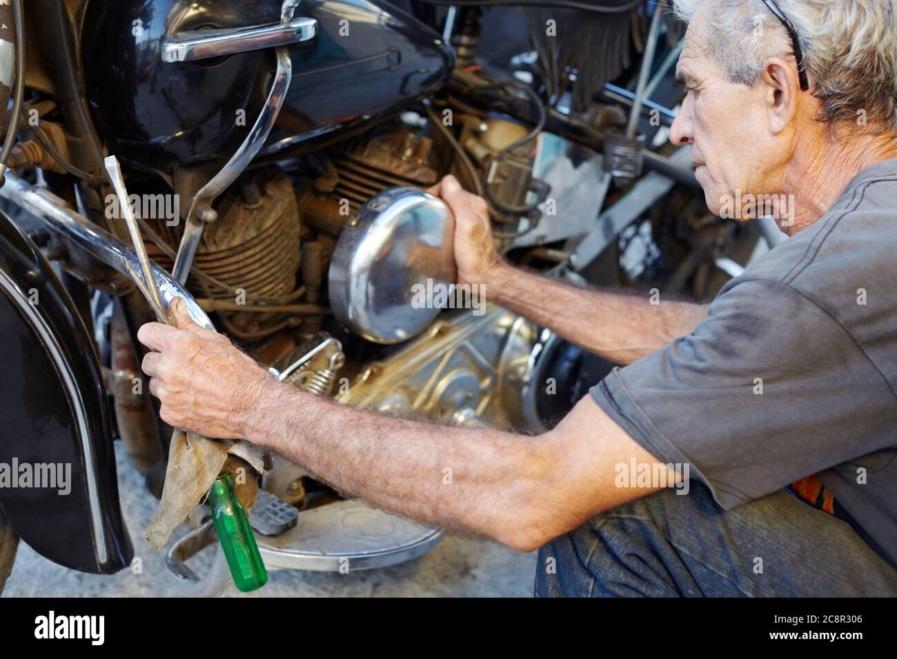 Senior Man che esamina la sua motocicletta e il suo motore di fissaggio Foto Stock