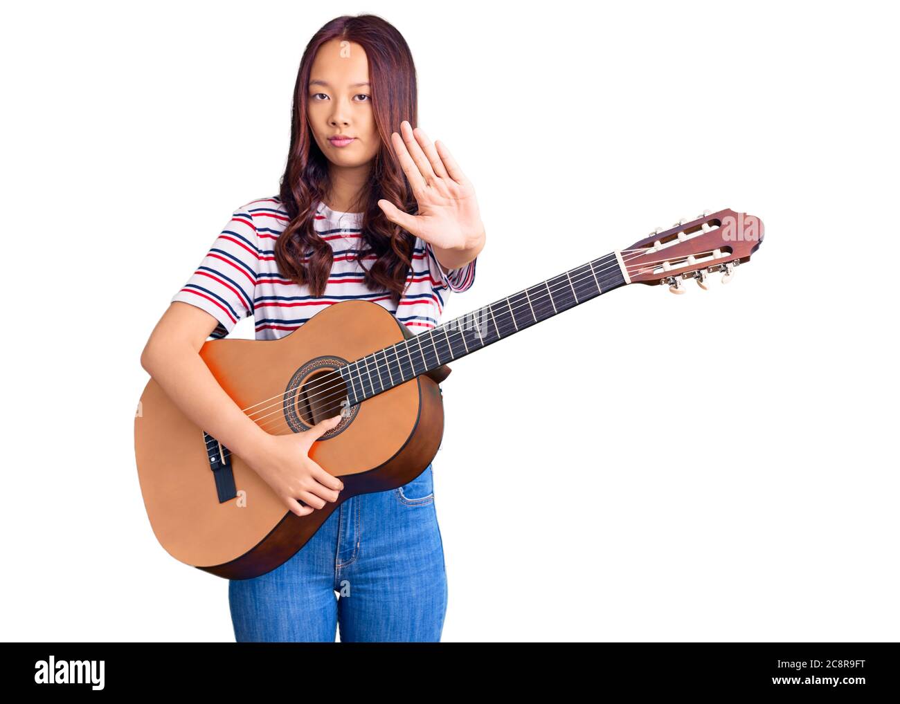 Giovane bella ragazza cinese che suona la chitarra classica con mano aperta  facendo stop segno con espressione seria e sicura, gesto di difesa Foto  stock - Alamy