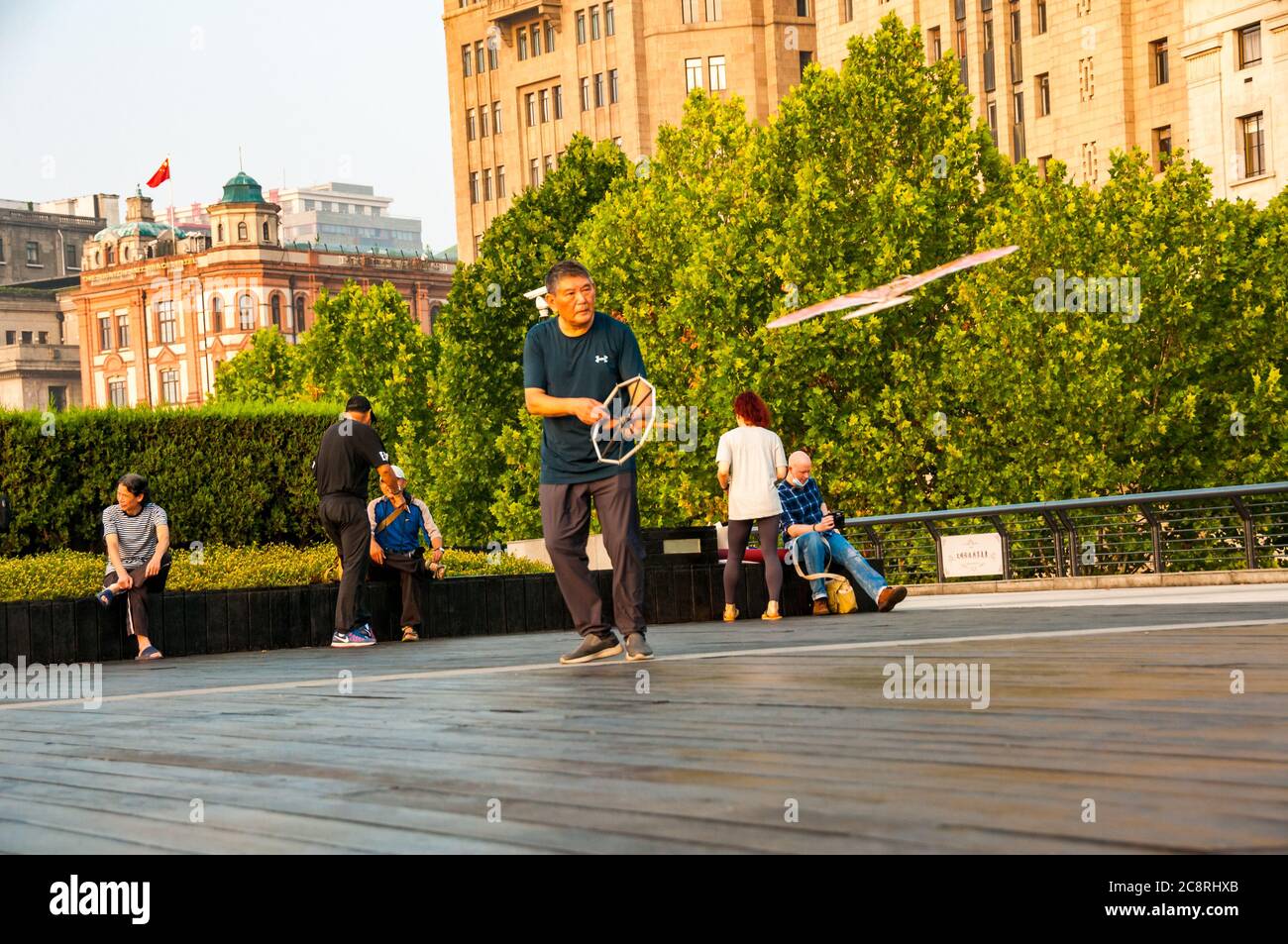 Un pensionato vola un aquilone a forma di uccello sulla passeggiata di Shanghai Bund la mattina presto. Foto Stock