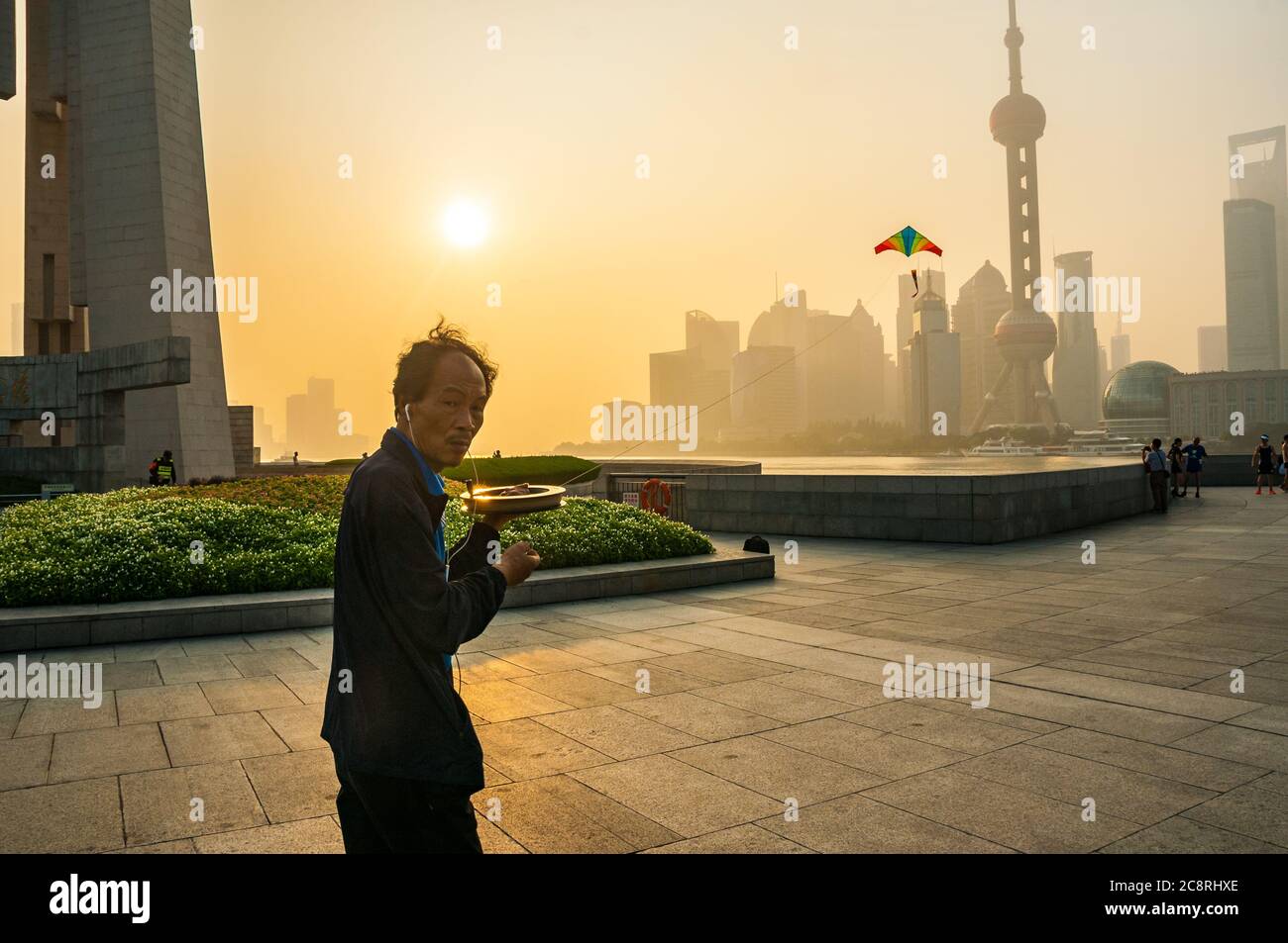 Un uomo che volava un aquilone la mattina presto sul Bund di Shanghai al Monumento agli Eroi del Popolo con lo skyline di Pudong sullo sfondo. Foto Stock