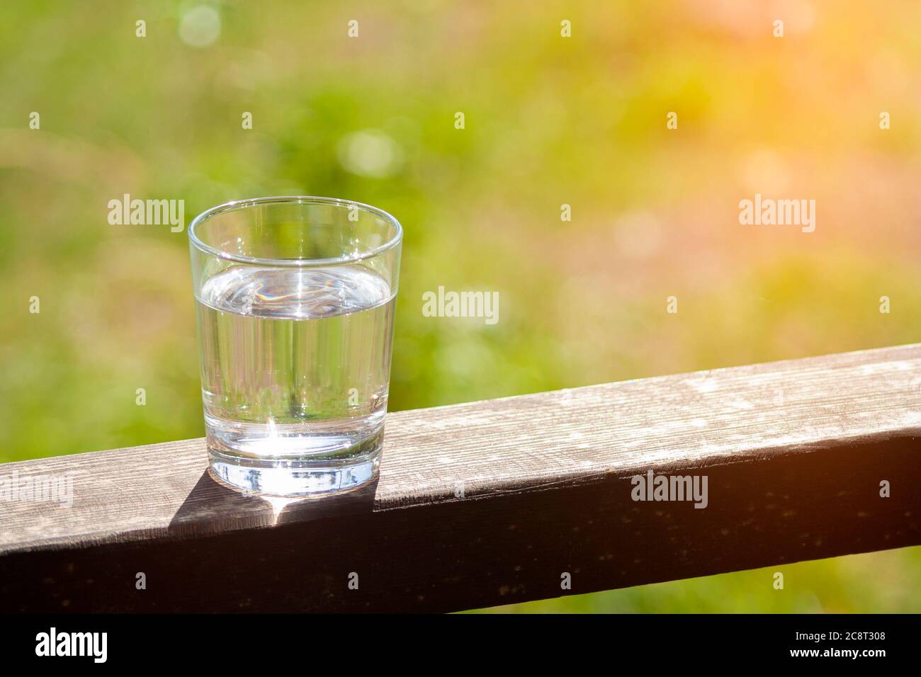 Il vetro dell'acqua si erge su una tavola di legno Foto Stock