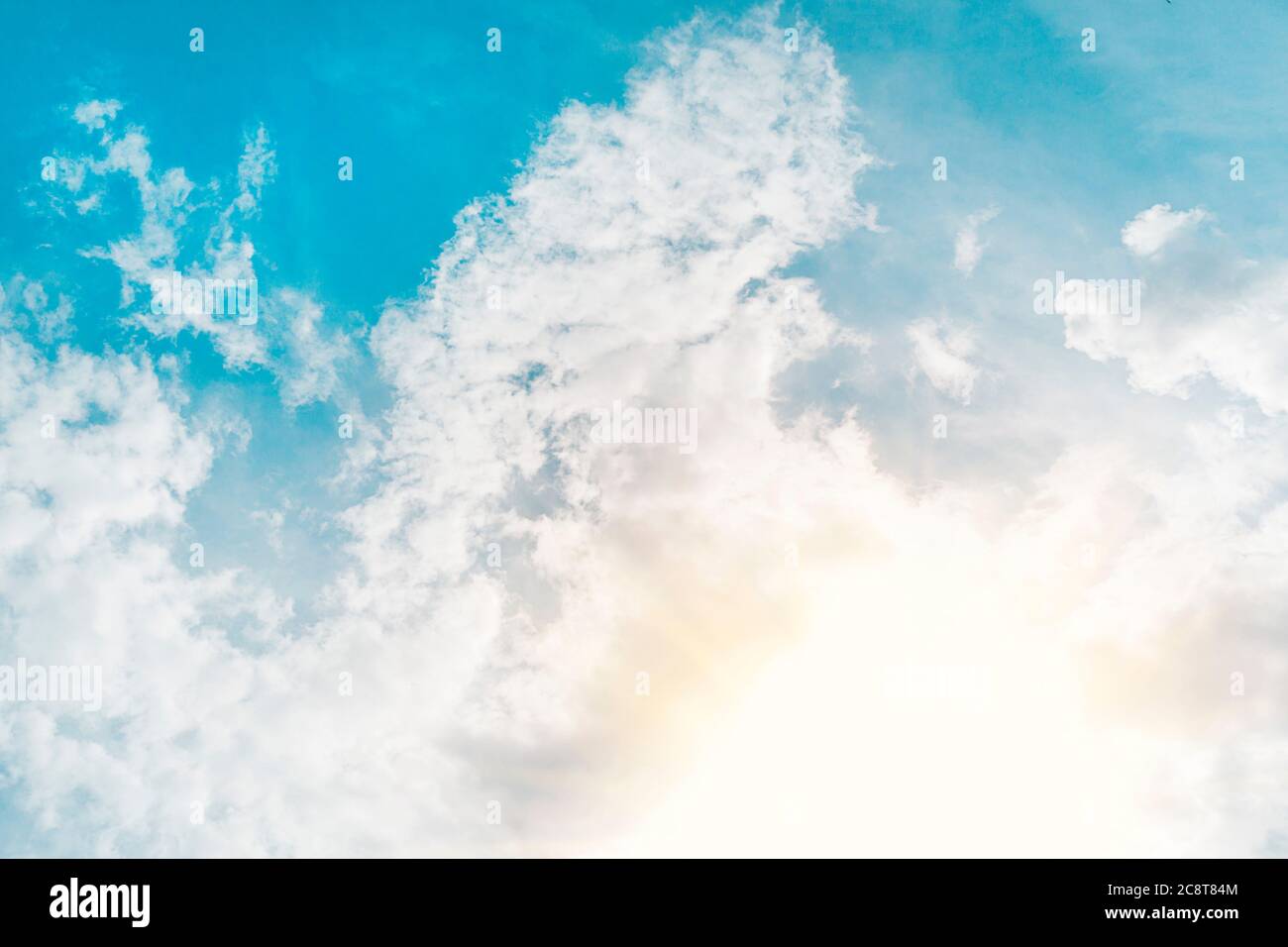scrutate i raggi del sole che brillano attraverso le nuvole bianche piume nel cielo blu. Bellissimo sfondo, cielo con nuvole e sole Foto Stock