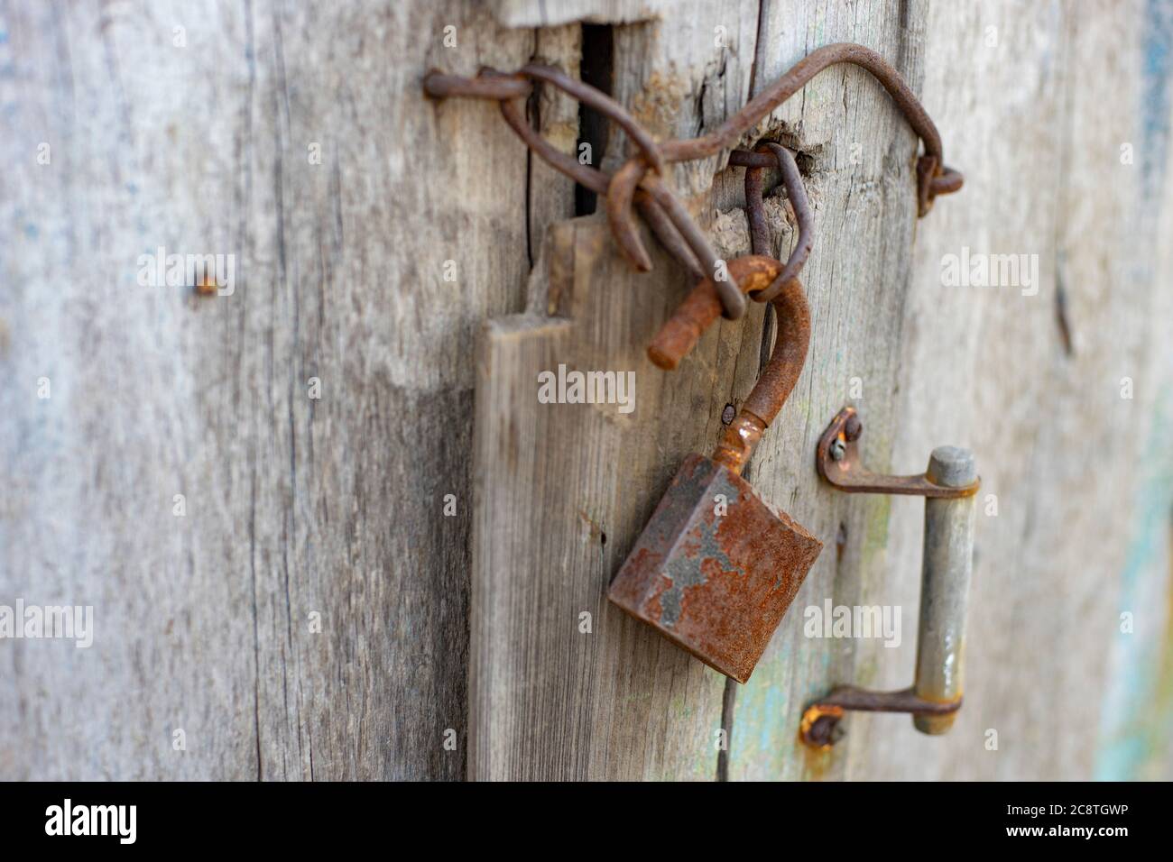 Vecchia porta in legno con maniglia arrugginita, gancio e serratura. Foto Stock