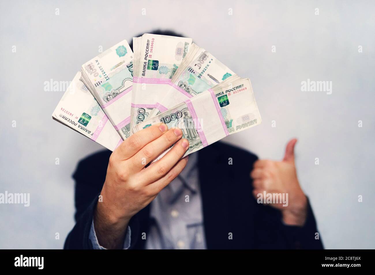 Millantesimo banconote di rublo russo in mano di un uomo. Mano maschile con un fascio di banconote. Trasferimento di denaro. Pollici in su come simbolo di un successo Foto Stock