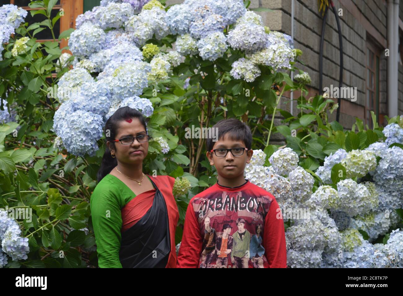 Una donna indiana, madre con il suo ragazzo adolescente nel suo giardino, messa a fuoco selettiva Foto Stock