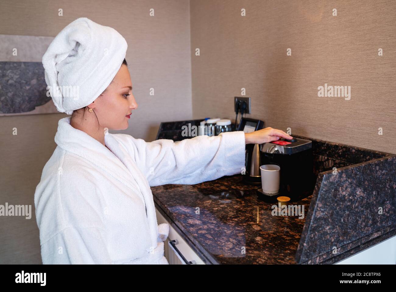 Giovane donna che preparava una tazza di caffè al mattino in camera d'albergo o a casa. Foto di alta qualità Foto Stock