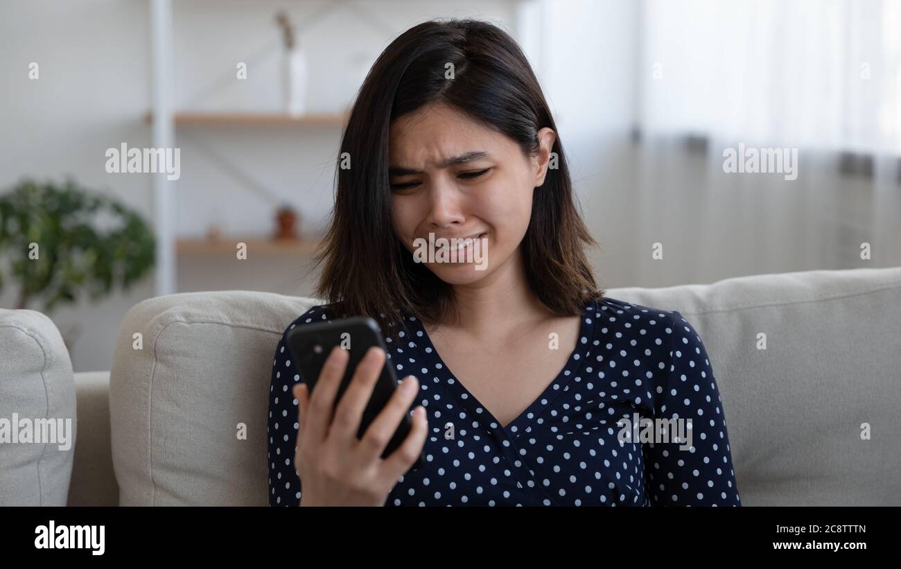 Infelice ragazza vietnamita afflitta con il messaggio del cellulare Foto Stock