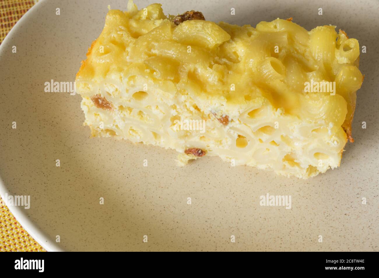 Vista ravvicinata su un pezzo di pudding di maccheroni cotto a mano con formaggio casolare e sultana Foto Stock