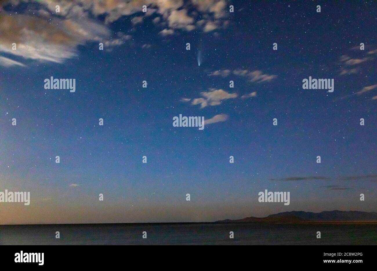 La Cometa NEOWISE nel cielo sopra le montagne del promontorio sulla destra e l'isola di Fremont di fronte a loro e il Grande Lago Salato. Foto Stock