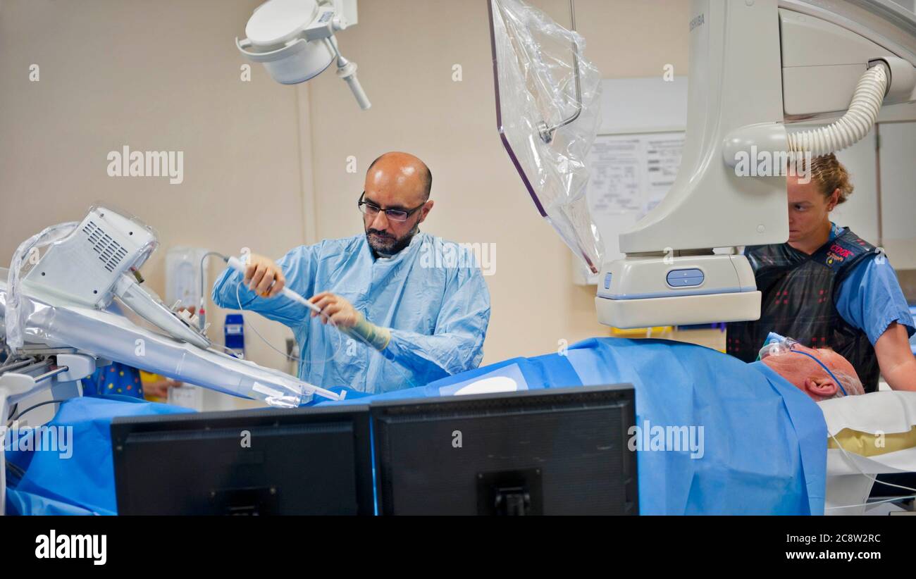 Il chirurgo prepara un catetere per l'inserimento controllato a distanza per correggere i ritmi cardiaci irregolari Foto Stock