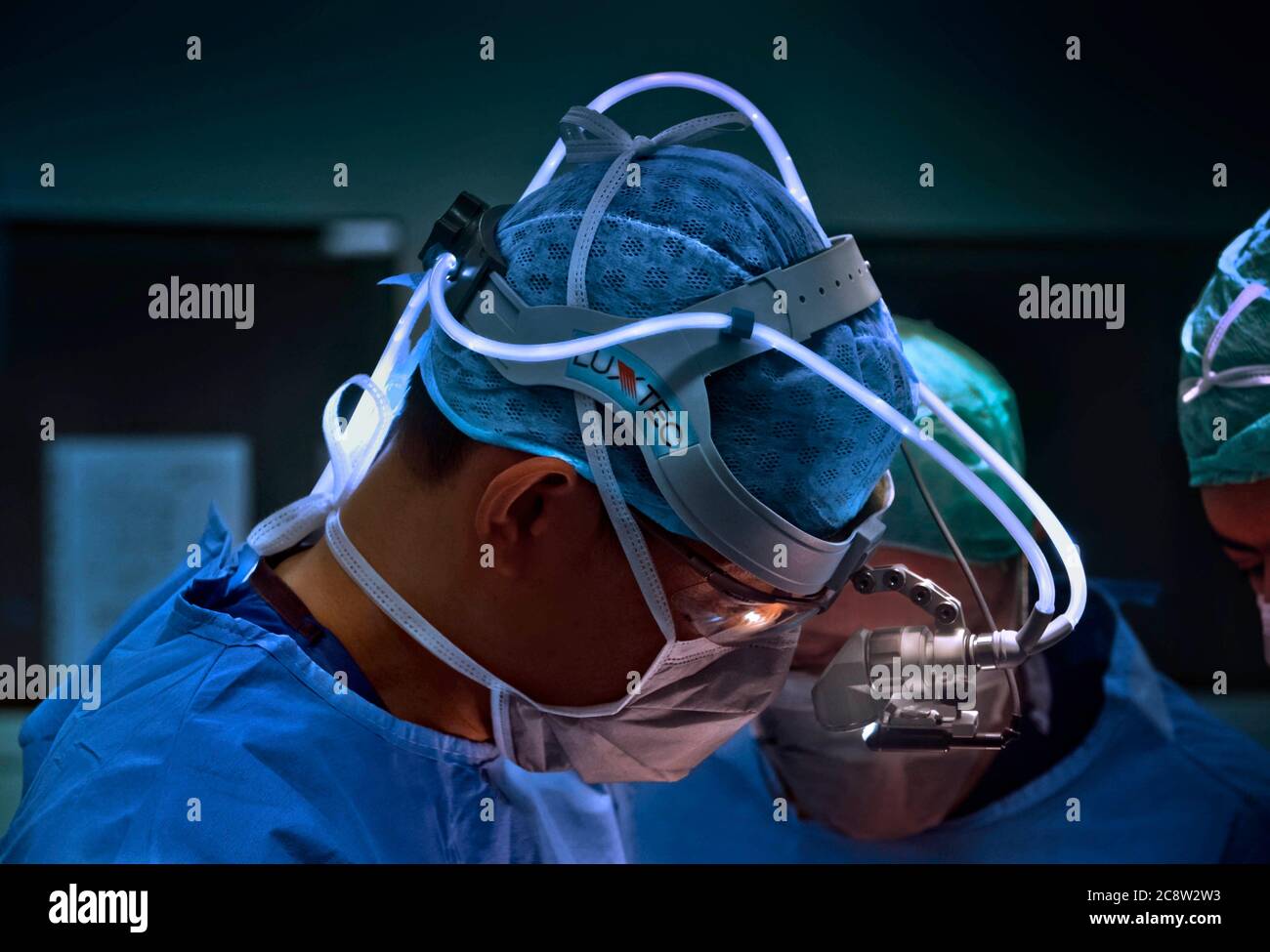 Il chirurgo esegue un'operazione toracica utilizzando una luce testa a fibra ottica. Foto Stock