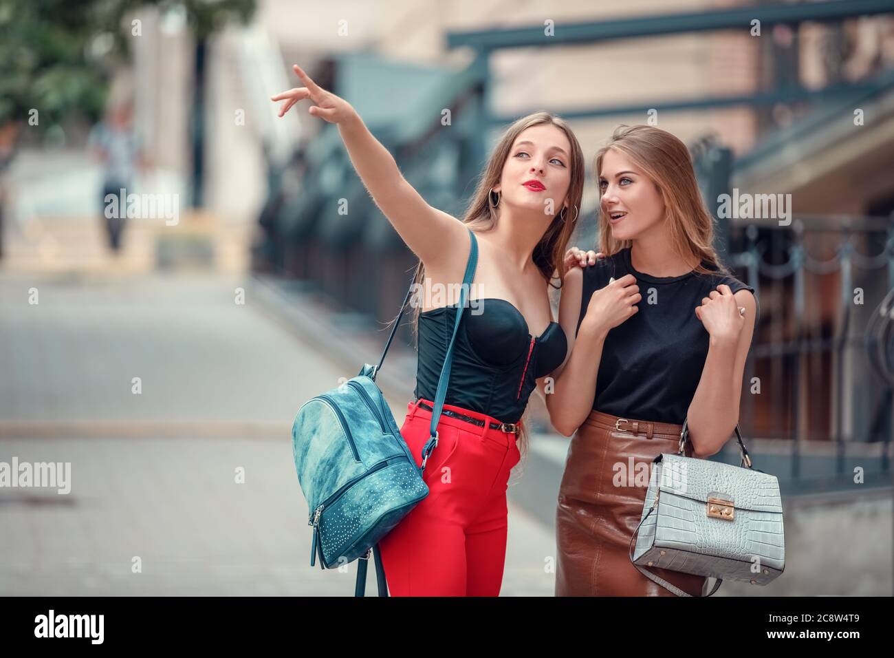 due allegre donne turisti moderni mentre si vedono nella città vecchia. una donna indica una vista, e anche un'altra donna entusiasta guarda in su. Foto Stock