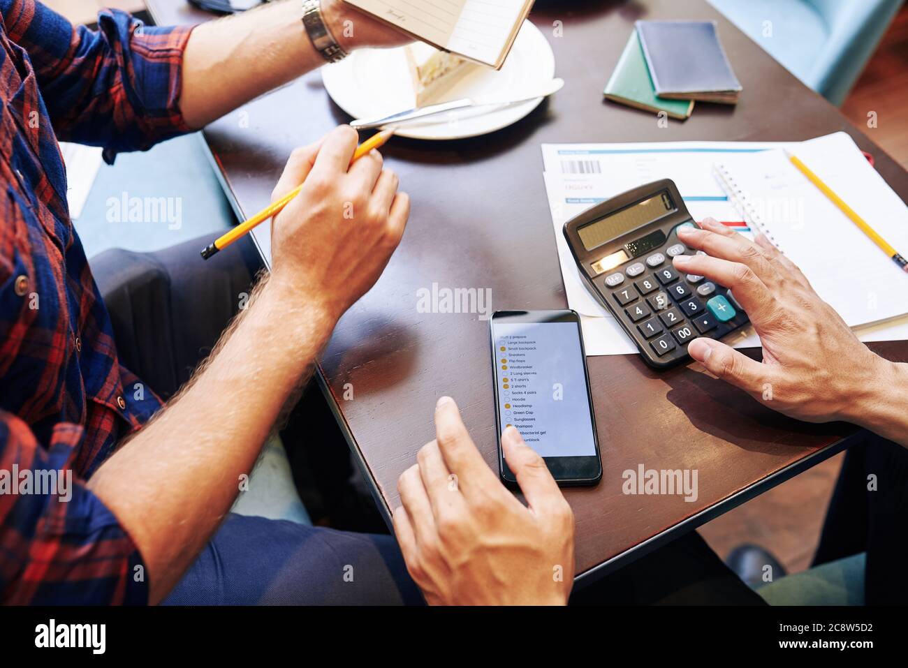 Immagine ravvicinata degli amici che fanno la lista di imballaggio e calcolano le scadenze quando pianificano un viaggio insieme Foto Stock