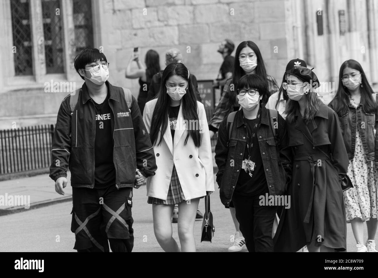 Gruppo di studenti asiatici che camminano lungo una strada urbana indossando maschere, York, North Yorkshire, Inghilterra, Regno Unito. Foto Stock