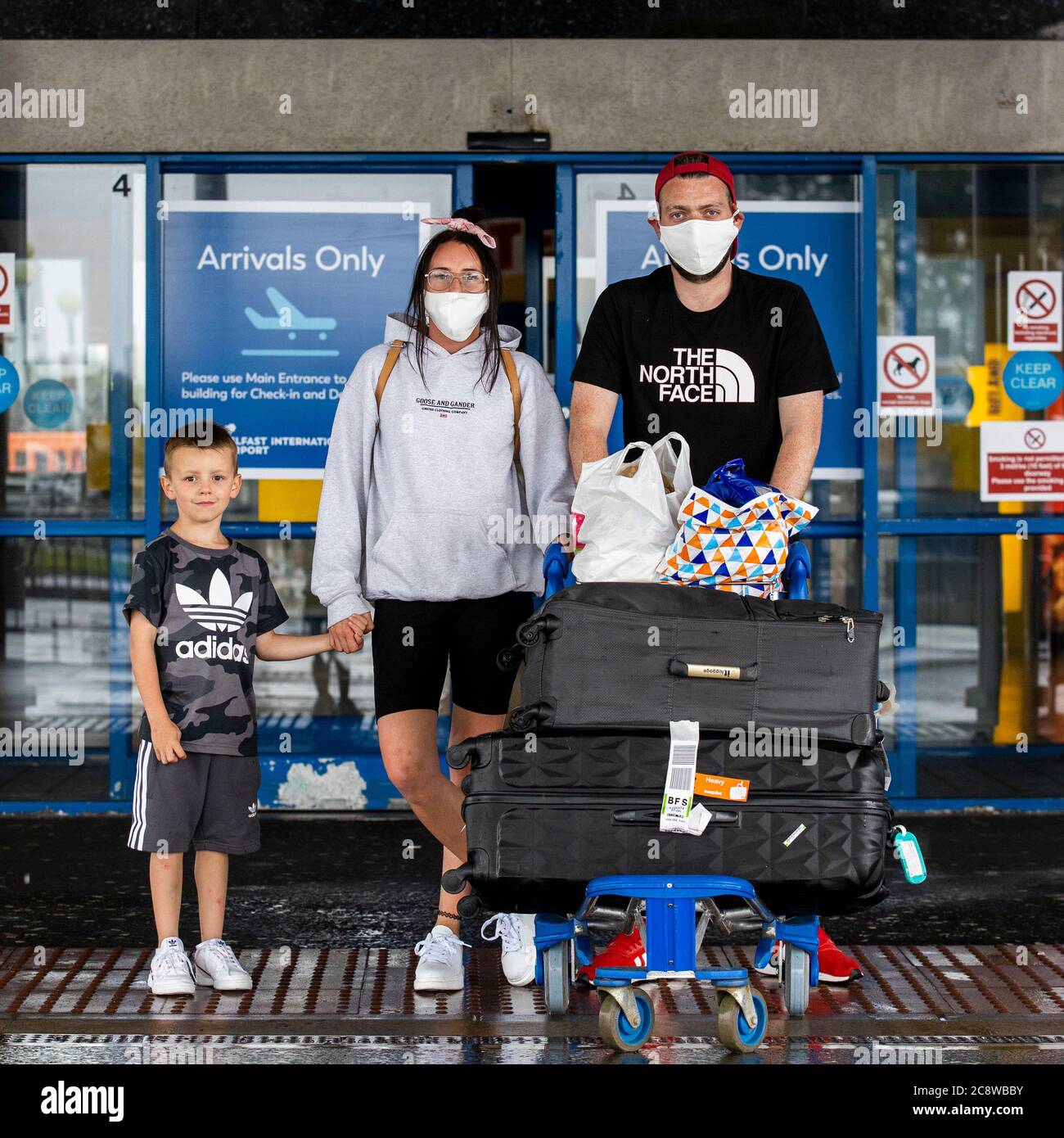 Christopher Andres Halliday con il suo partner Melissa Campbell e il loro figlio di sei anni, Lewis Andres, che vive a Belfast lasciando Belfast International Airport dopo essere arrivato su Easyjet 10 EJU6672 volo da Barcellona, Spagna. L'esecutivo dell'Irlanda del Nord è destinato a riunirsi più tardi per discutere una decisione di introdurre la quarantena per coloro che arrivano nella regione dalla Spagna. Foto Stock