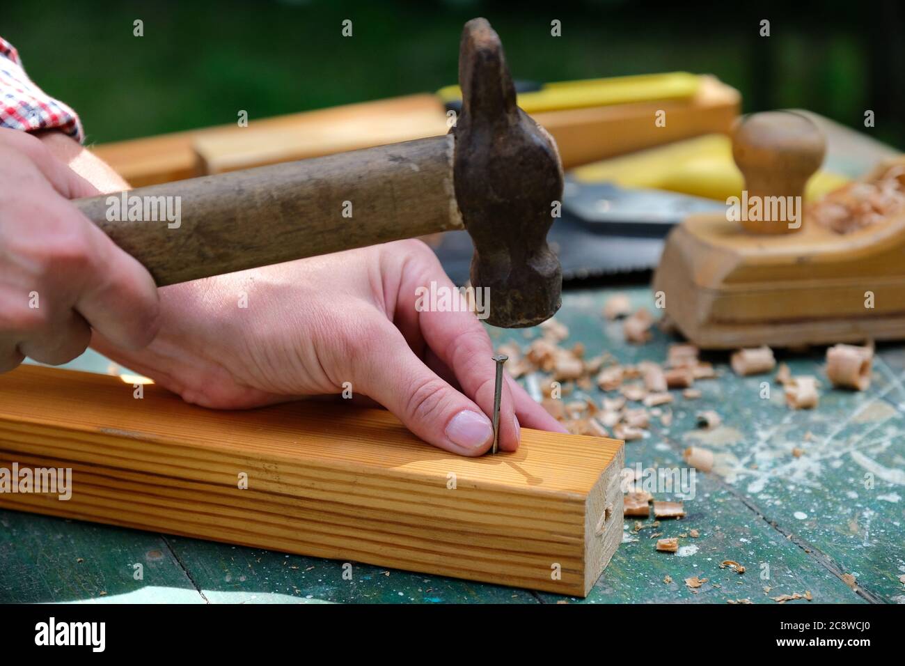 Le mani del falegname con il martello colpiscono il chiodo sul legno.  Concetto di legno Foto stock - Alamy