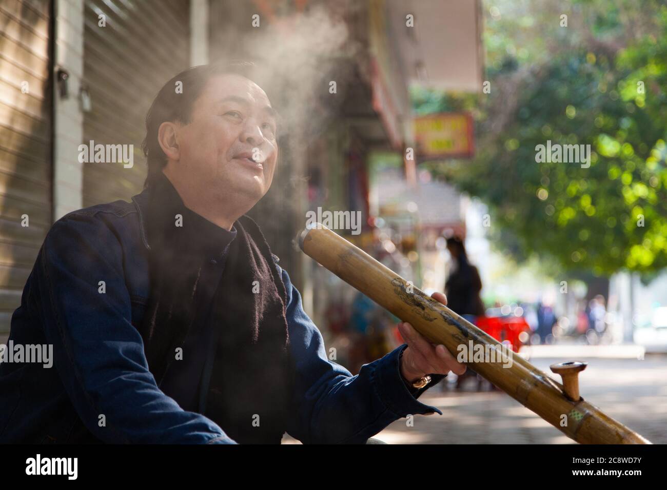 Hanoi Vietnam 20/12/2013 uomo che fuma il tubo tradizionale in prima mattina sulla strada Foto Stock