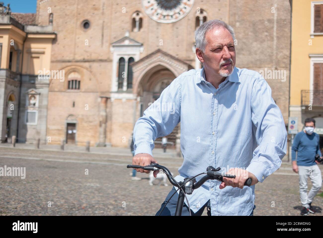 Uomo che cavalcava la sua bicicletta in una piazza della città Foto Stock