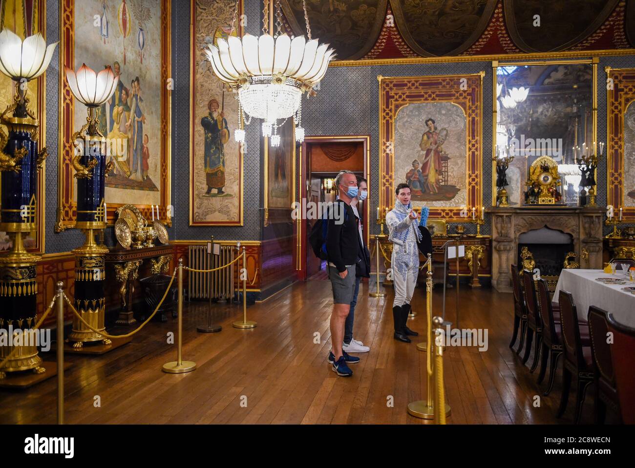 Brighton UK 27 luglio 2020 - Zack Pinsent dà il benvenuto ai primi visitatori James Stenning (a sinistra) e George Brooker nella Sala banchetti del Royal Pavilion di Brighton questa mattina dopo il blocco del coronavirus . La riapertura di questo iconico edificio, il simbolo e il cuore di Brighton & Hove, è un altro passo verso la città di tornare a una nuova normalità. : Credit Simon Dack / Alamy Live News Foto Stock