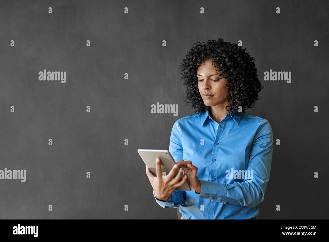 Donna d'affari che lavora con un tablet digitale mentre si trova davanti a una lavagna vuota Foto Stock