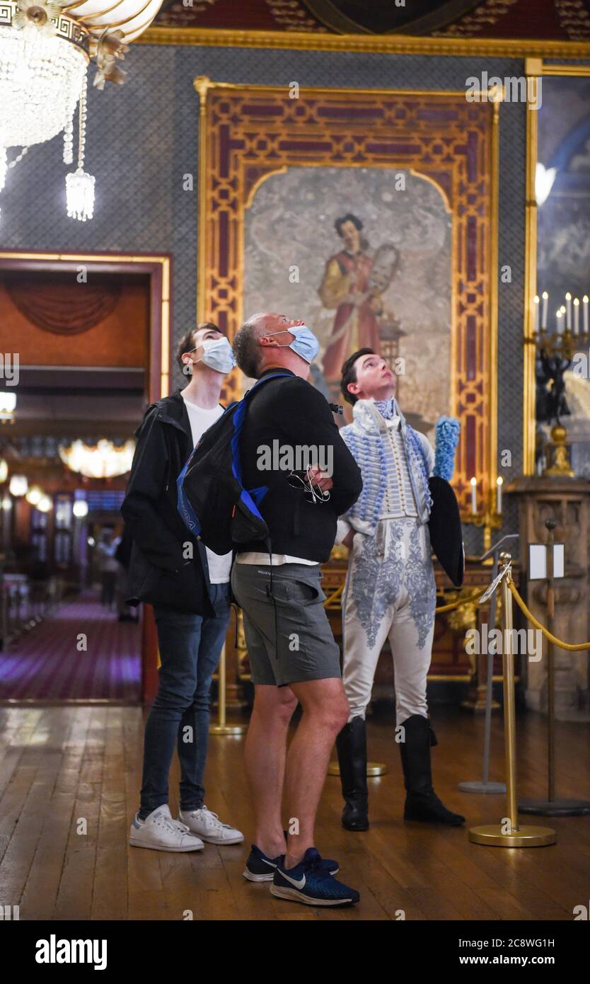 Brighton UK 27 luglio 2020 - Zack Pinsent dà il benvenuto ai primi visitatori James Stenning (centro) e George Brooker nella sala banchetti del Royal Pavilion di Brighton questa mattina dopo il blocco del coronavirus . La riapertura di questo edificio iconico, il simbolo e il cuore di Brighton & Hove, è un altro passo verso la città di ritornare ad una nuova normalità: Credit Simon Dack / Alamy Live News Foto Stock