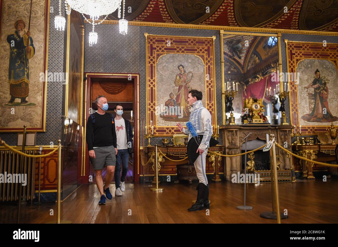 Brighton UK 27 luglio 2020 - Zack Pinsent dà il benvenuto ai primi visitatori James Stenning (a sinistra) e George Brooker nella Sala banchetti del Royal Pavilion di Brighton questa mattina dopo il blocco del coronavirus . La riapertura di questo iconico edificio, il simbolo e il cuore di Brighton & Hove, è un altro passo verso la città di tornare a una nuova normalità. : Credit Simon Dack / Alamy Live News Foto Stock