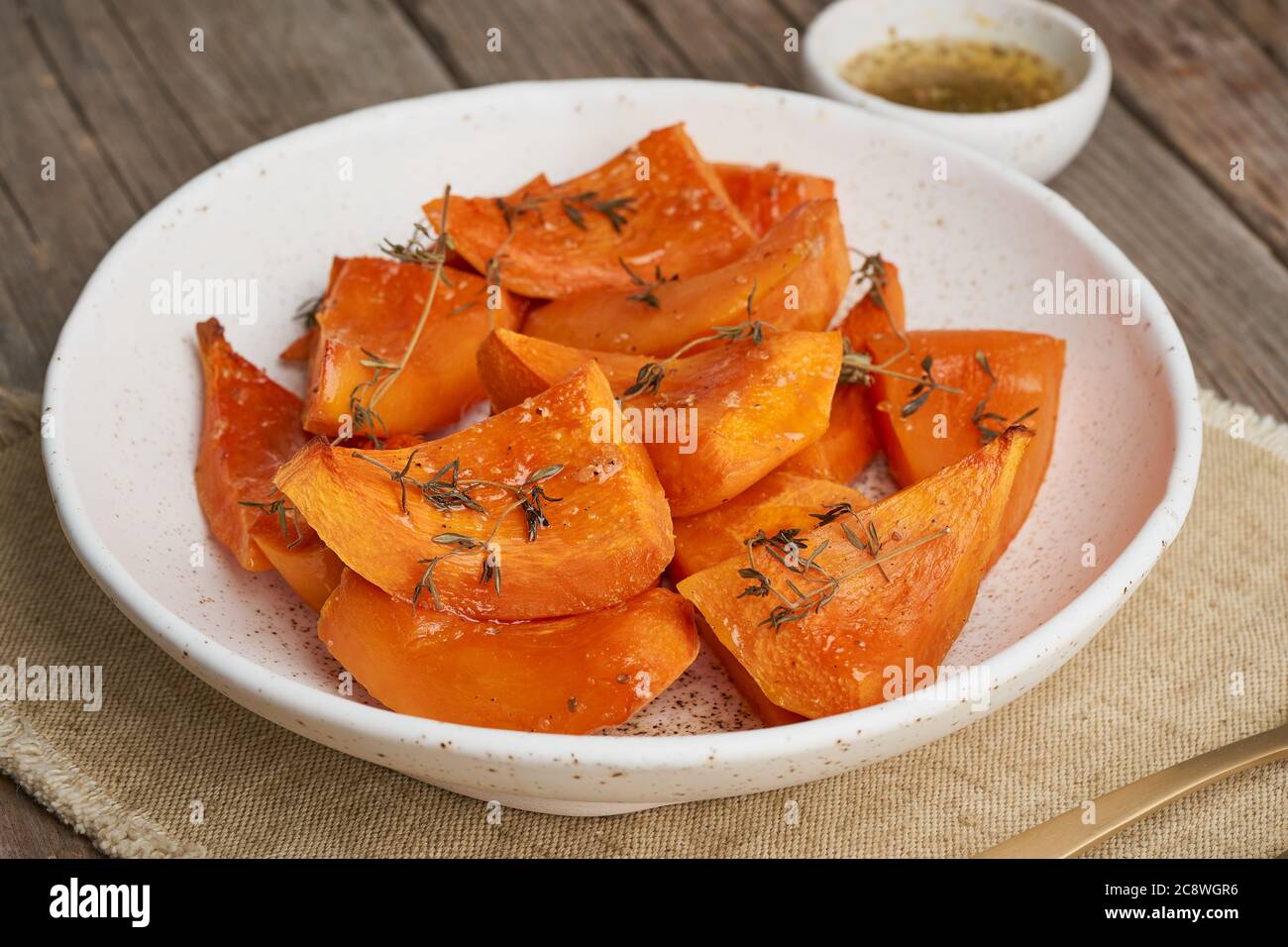 zucca arrosto, pezzi in piastra con miele e condimenti, antico rustico legno scuro tavolo Foto Stock