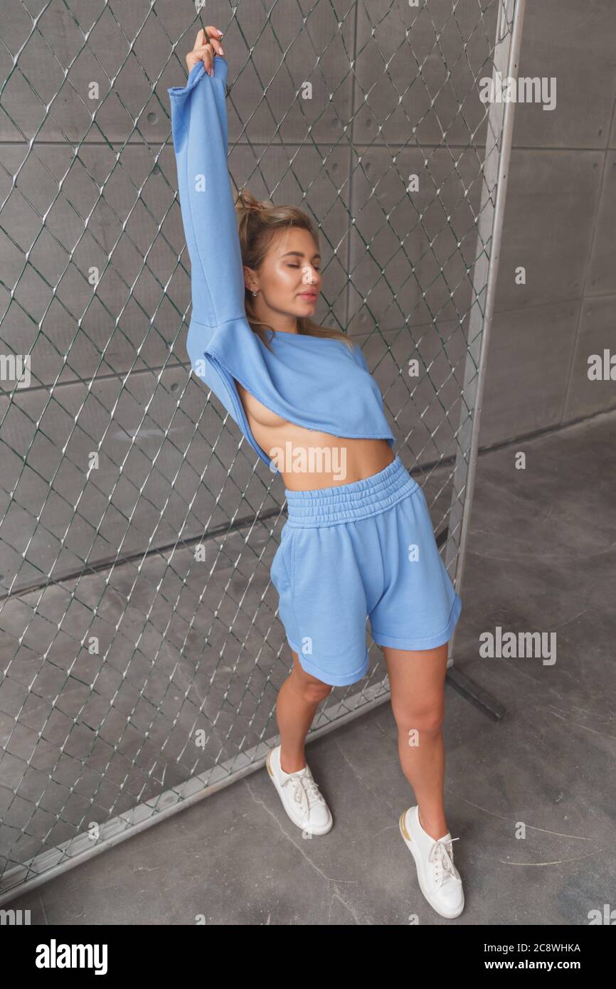 Giovane bionda caucasica in un look sportivo alla moda sulla donna. Pantaloncini  e felpa blu Foto stock - Alamy
