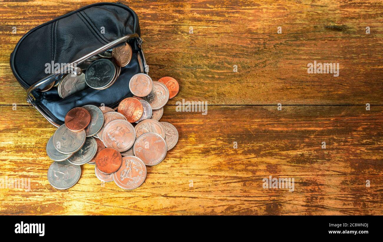 Apri il portafoglio a tasca in pelle nera pieno di monete. Crisi finanziaria, povertà, mancanza di denaro. Su sfondo o tavolo di legno. Disposizione piatta. Vista dall'alto. C Foto Stock