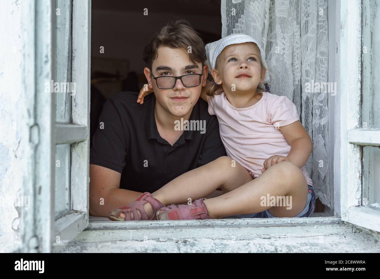 fratello maggiore e sorella minore nella finestra di una vecchia casa di  villaggio Foto stock - Alamy