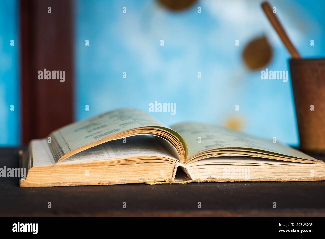Apri il libro su un tavolo con sfondo astratto autunnale sulla finestra per un'accogliente lettura a casa Foto Stock