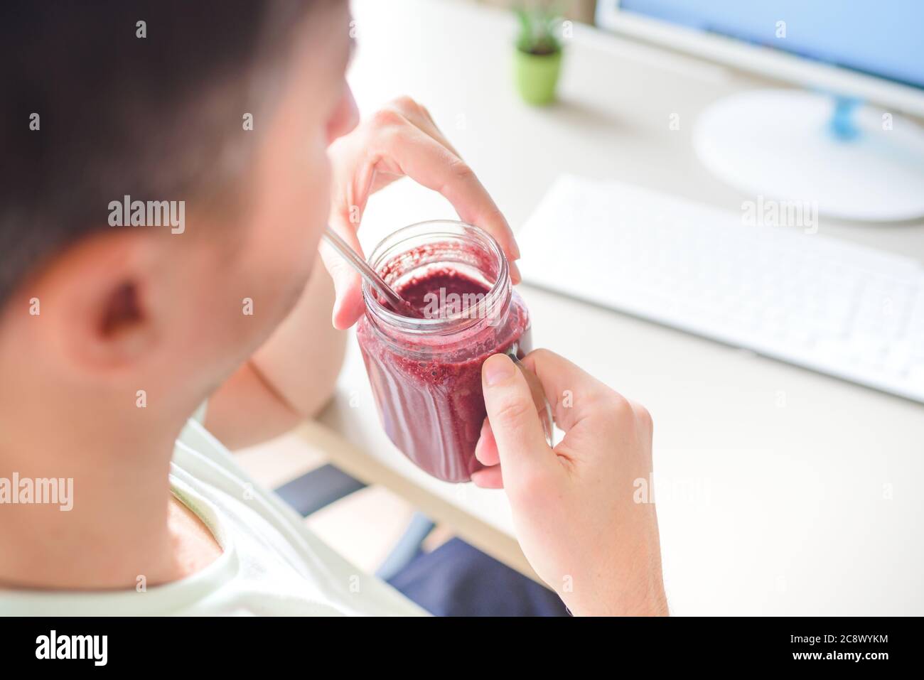 uomo che lavora al computer e beve frullato a casa ufficio Foto Stock