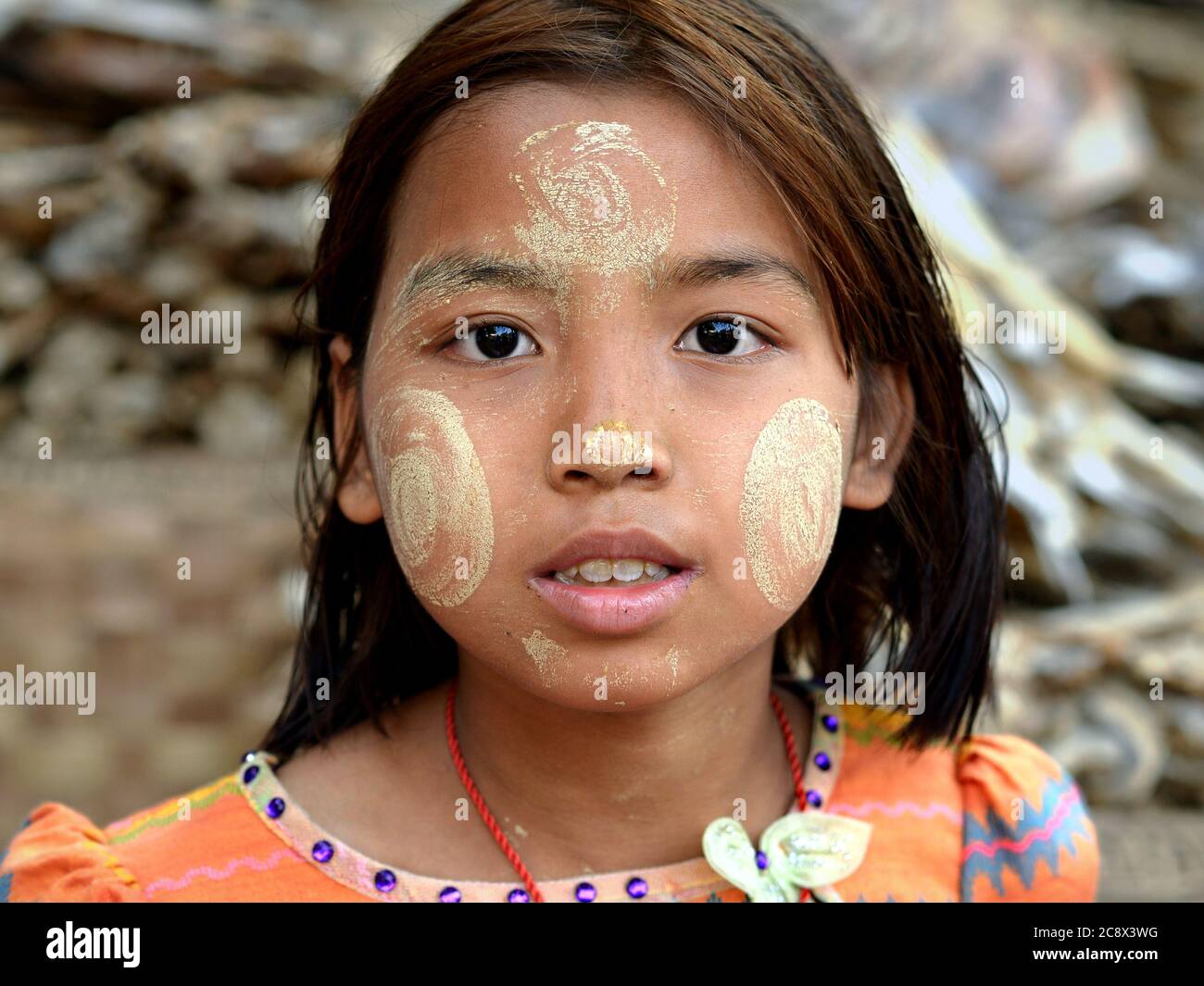 Giovane ragazza birmana con naturale thanaka faccia cosmetic in tutto il suo viso gapes alla macchina fotografica. Foto Stock