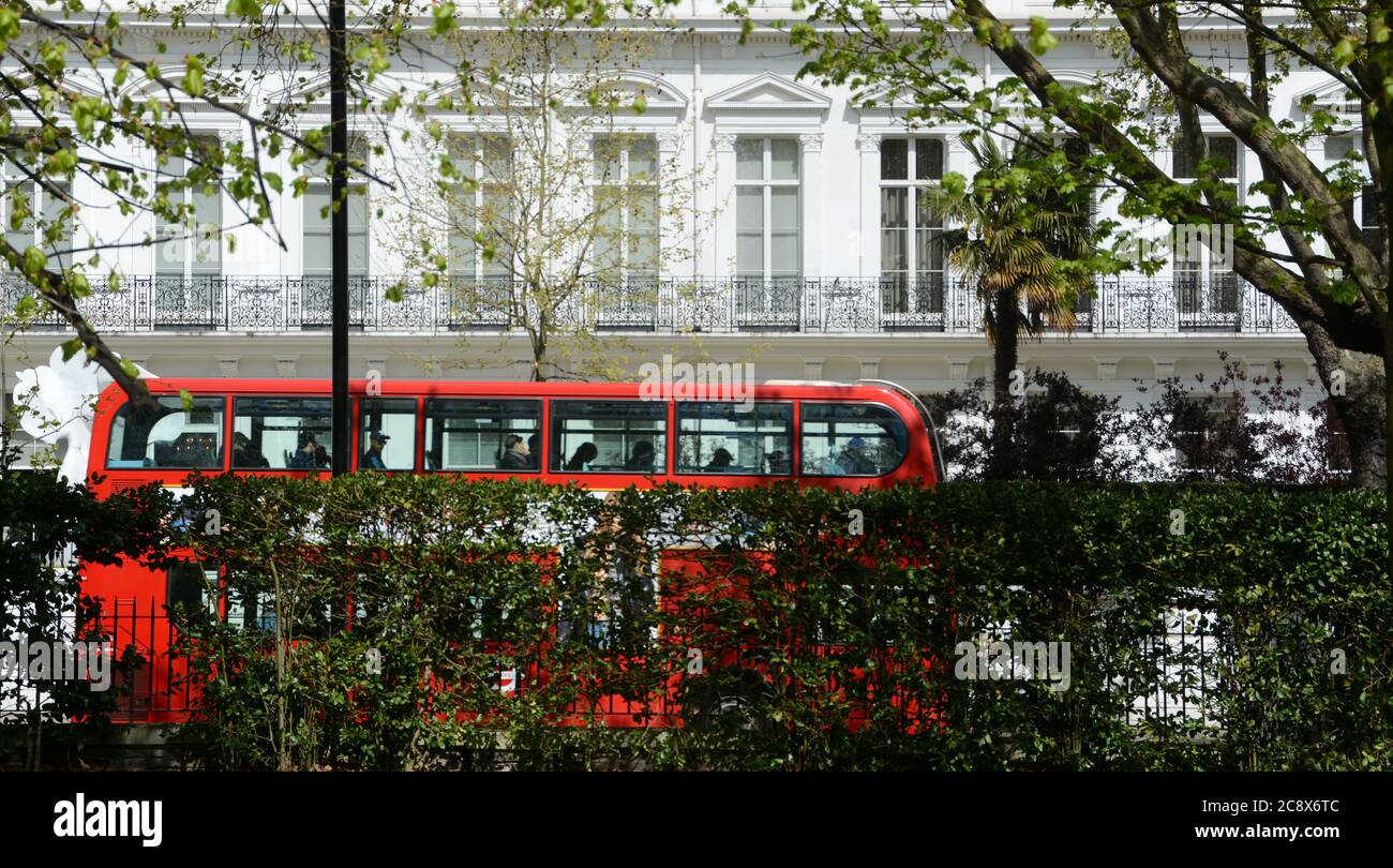 Autobus a due piani rosso di Londra nel cuore di Kensington su viale con bandiere di nazioni. Foto Stock