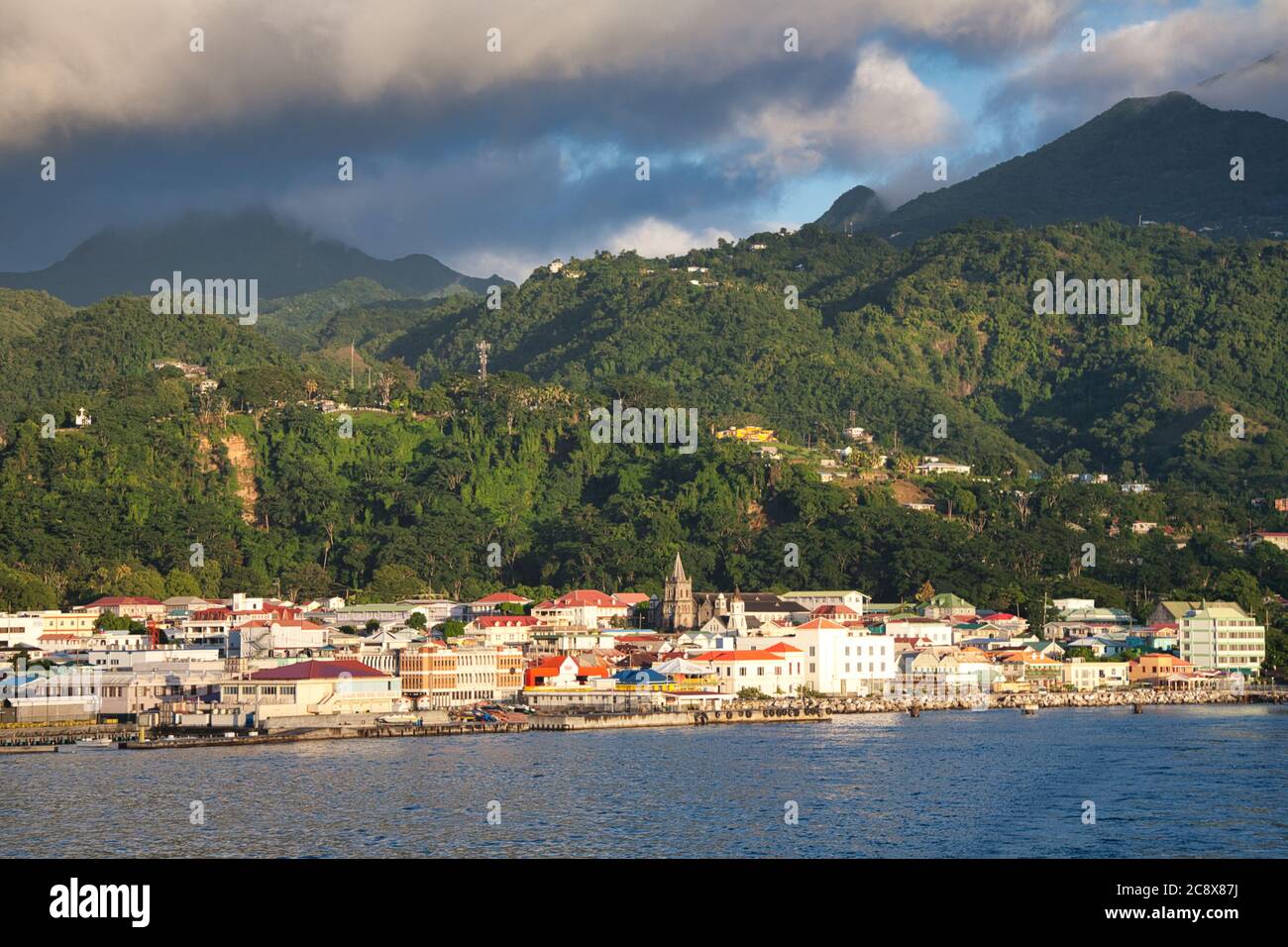 La città di Roseau sull'isola di Dominica vista dal mare con un paesaggio di colline boscose oltre e nuvole in un cielo blu sopra, i Caraibi Foto Stock