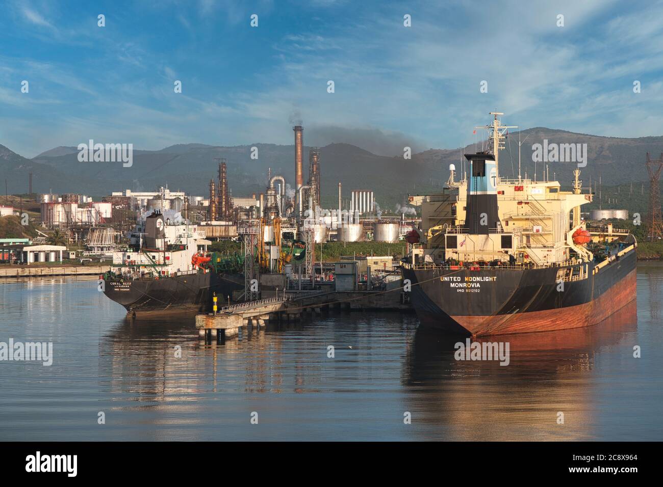 Santiago, Cuba, due petroliere attraccate in una raffineria di petrolio con serbatoi di stoccaggio del petrolio sullo sfondo Foto Stock