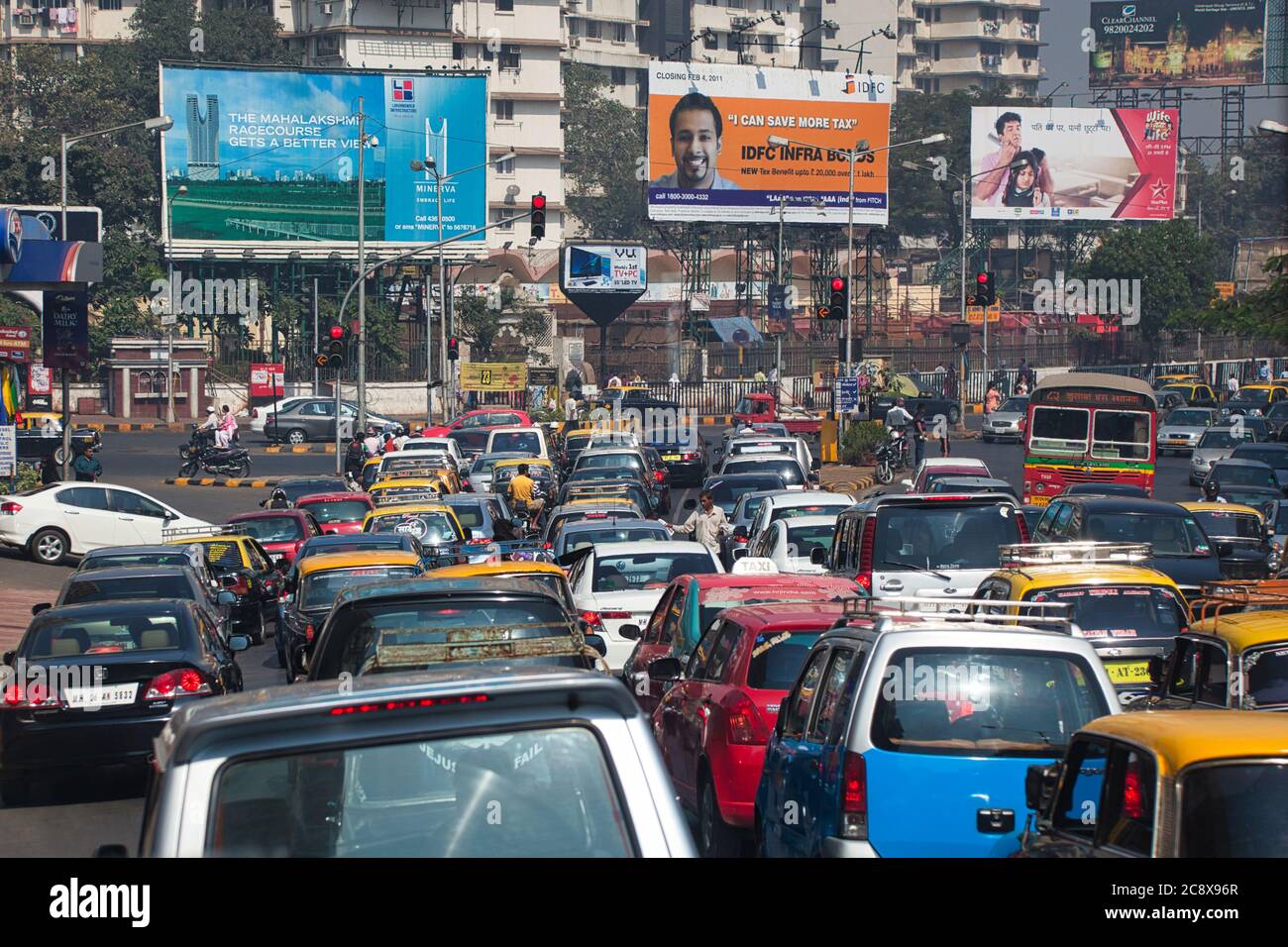 Mumbai, conosciuta anche come Bombay nello stato del Maharashtra in India, mostra una strada ostruita dal traffico con pubblicità in lontananza Foto Stock
